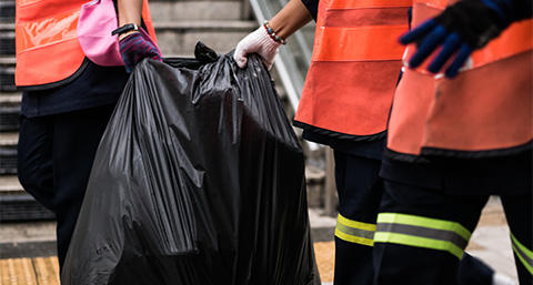 a group of waste removers holding a black bag